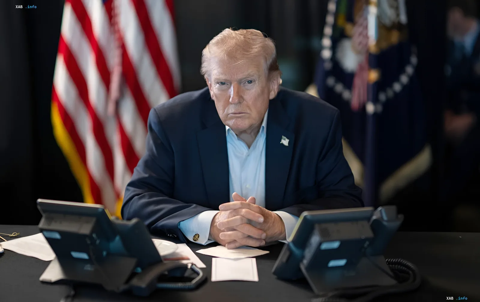 Дональд Трамп за столом з серйозним виразом обличчя, на фоні прапорів США — у контексті загрози потужного удару по Ірану після ракетної атаки