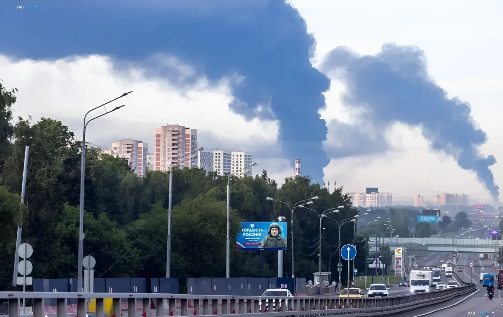Густой черный дым от пожара над российским городом на фоне жилых домов и дороги с движением, символизирующий удар по логистике Wildberries и паралич торговли