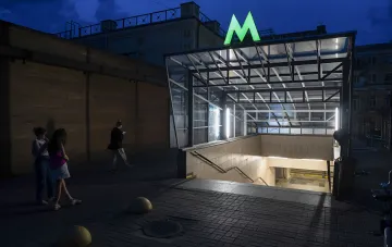 Eingang zur Kyjiver U-Bahn-Station Kontaktova Ploshcha bei Nacht, beleuchtetes grünes M-Logo, Menschen am Eingang — Illustration zum Artikel darüber, wie die U-Bahn 56.000 Kiewer während eines nächtlichen Angriffs rettete