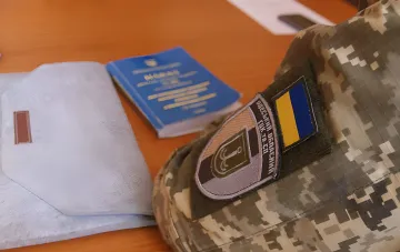 Символическое изображение: военная форма с нашивкой ТЦК Одесса, паспорт и конверт — метафора взятки за снятие с розыска