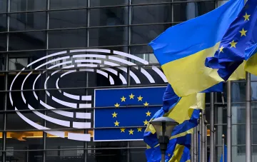 Флаги Украины и Европейского Союза перед зданием Совета ЕС, символизирующие обновленный план поддержки Украины на 2026 год