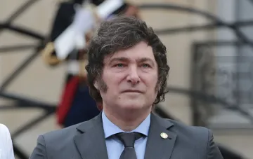 Президент Аргентины Хавьер Милей в официальном костюме на фоне государственного здания, обсуждающий новые правила для иностранцев