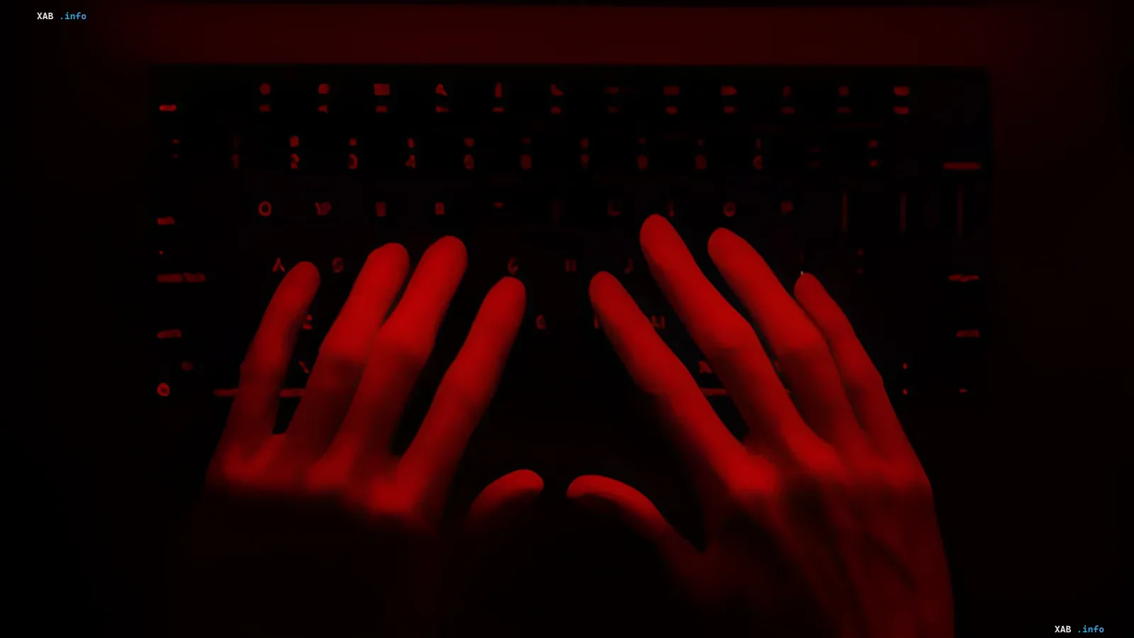 Hacker's hands on a keyboard in red light, symbolizing cyber threats of 2026