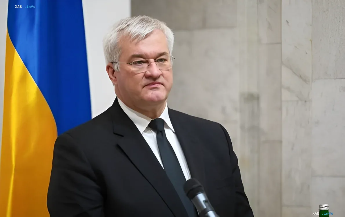 Ukrainian Foreign Minister Andriy Deshchytsia in front of the Ukrainian flag, discussing hybrid warfare and Russian propaganda