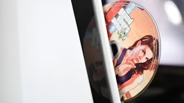 Диск с игрой Grand Theft Auto V в дисководу PlayStation, символизирующий отказ Sony от физических носителей