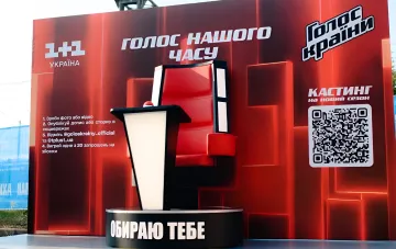 Червоний стіл тренера з шоу «Голос країни» на промо-стенді 14-го сезону з QR-кодом для кастингу та написом «Обираю тебе», що символізує повернення Тіни Кароль