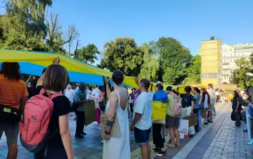 Участники митинга в Киеве держат огромный украинский флаг, требуя возвращения Алексея Федорова на пост министра обороны