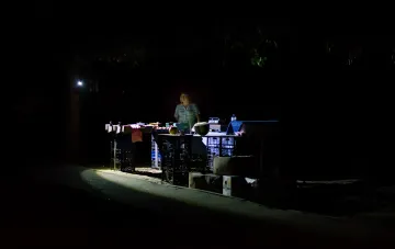 Vendor at a roadside stall in Crimea illuminated by a single lamp, illustrating the impact of power supply restrictions