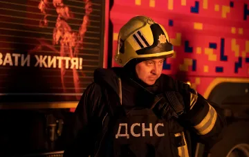 Спасатель ДСНС в защитной экипировке у пожарной машины после атаки на терминал «Новой почты» в Полтаве