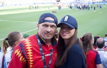 Александр Усик и его жена на стадионе во время футбольного матча, демонстрируя семейную гармонию после карьеры в боксе