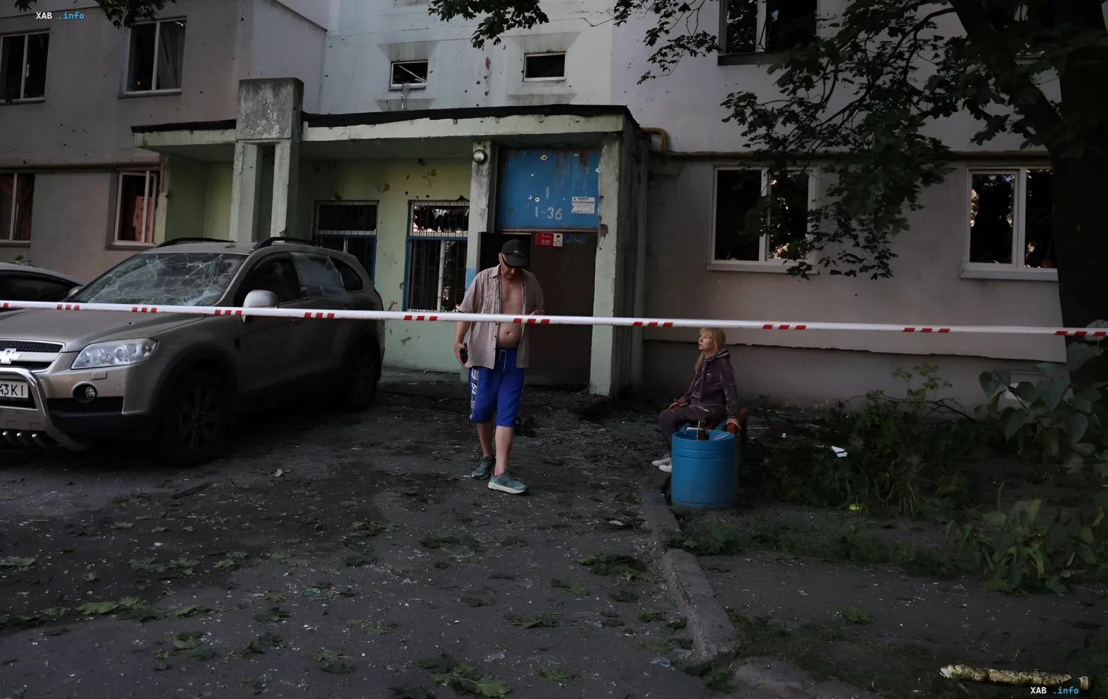 Folgen des ballistischen Anschlags in Kiew: beschädigtes Gebäude, zerstörtes Auto und Menschen hinter Absperrband