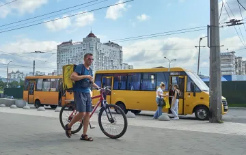Желтая маршрутка на остановке в Киеве: пассажиры садятся в автобус, иллюстрируя новость о подорожании общественного транспорта