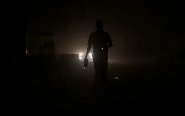 Силуэт человека на фоне ночного неба с огнями вдали, символизирующий ночную охоту дронов ВСУ по энергетике в Зугре, Бердянске и Крыму
