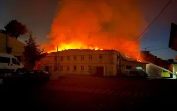 Пожар на базе «Киевмедспецтранса» в Киеве после ночной ракетной атаки, охваченное пламенем здание и работающие пожарные машины
