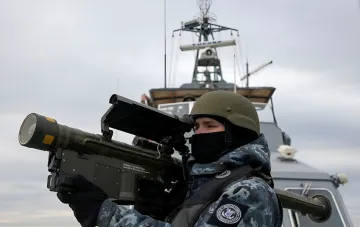 Ukrainian sailor with anti-ship missile system aboard patrol boat — symbol of defending port infrastructure from Russian strikes