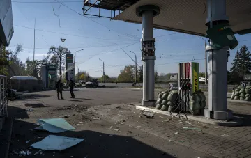 Разрушенная заправочная станция в Украине после российского обстрела: поврежденные колонки, мешки с песком и военные на фоне