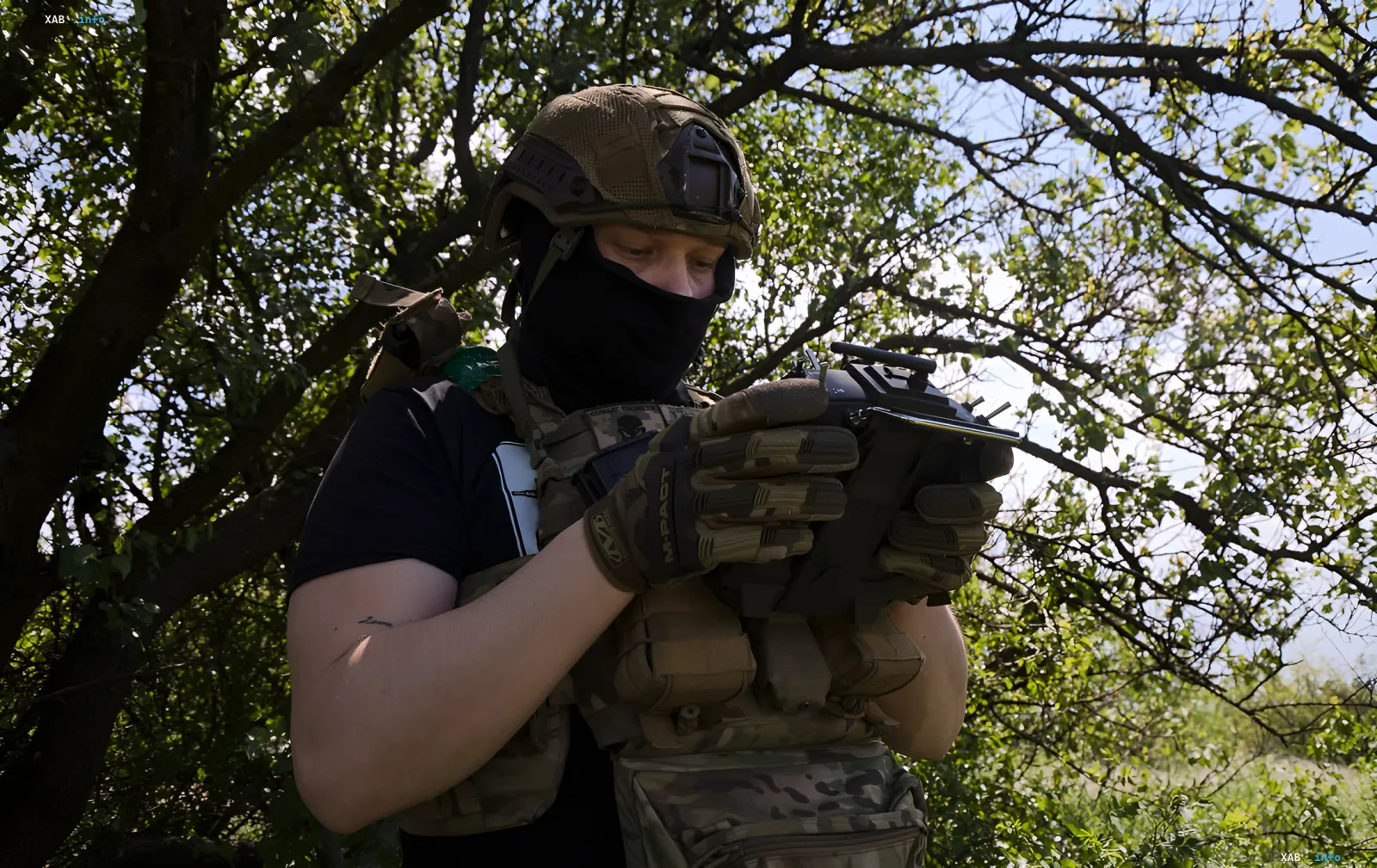 Боец ВСУ в камуфляже и маске управляет пультом дистанционного управления беспилотником в лесу, готовясь к удару по логистическим объектам в Крыму