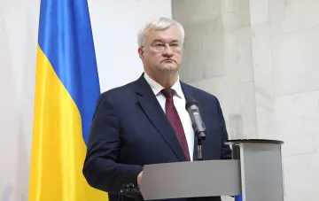 Министр обороны Украины Алексей Резников выступает с заявлением на фоне украинского флага, требуя ускорения поставок систем ПВО после массированного удара по Киеву