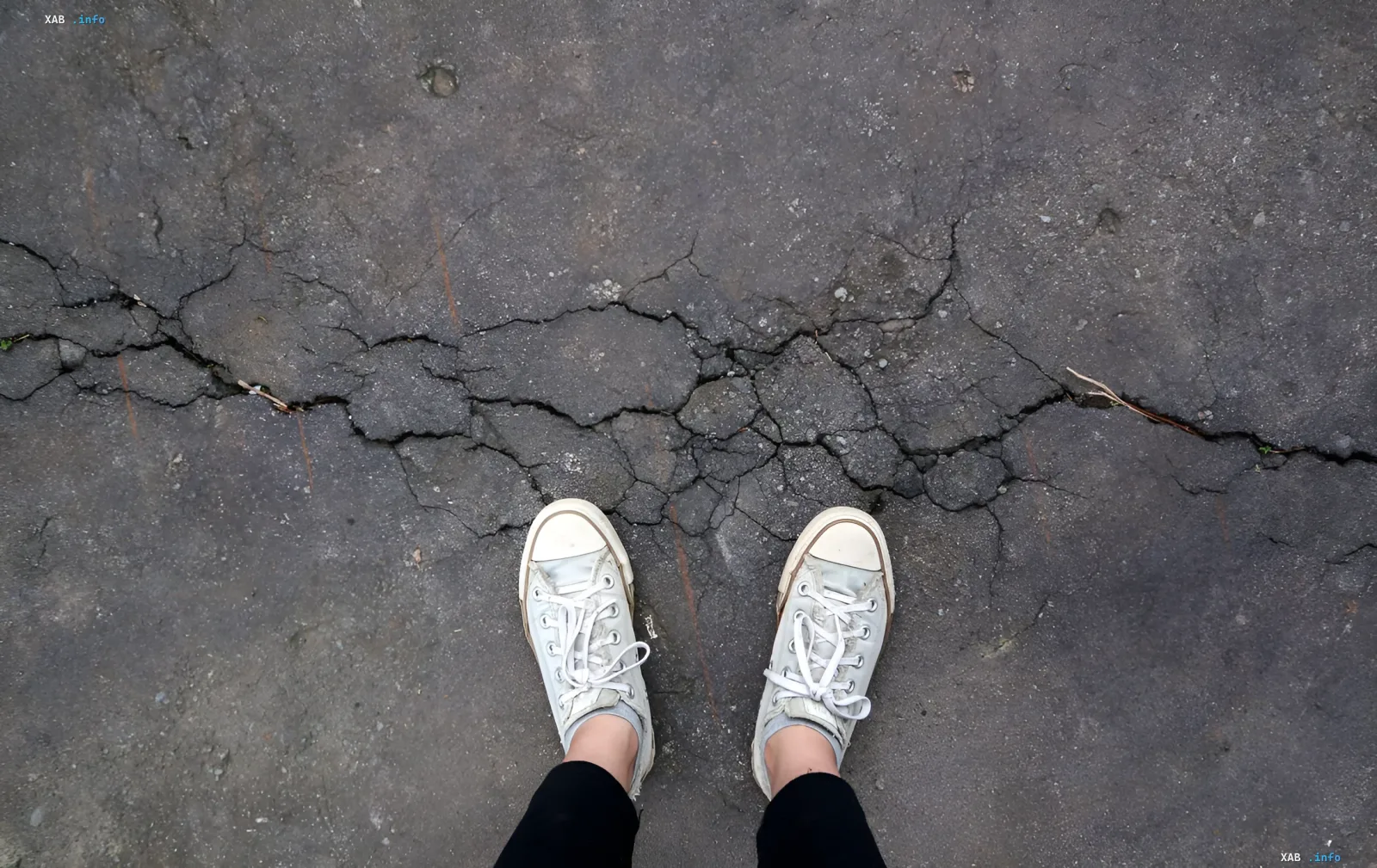 Risse im Asphalt vor weißen Turnschuhen — visuelle Metapher der Folgen des Erdbebens der Stärke 4,7 in Pozzuoli
