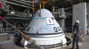 Космический корабль Boeing Starliner поднимается краном в сборочном цеху NASA в рамках подготовки к новому полету к МКС