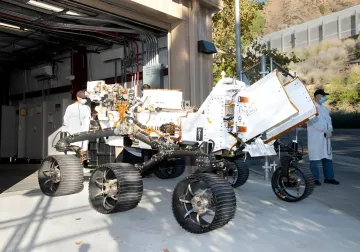 Lunar rover PROMISE in NASA assembly facility: engineers in lab coats inspect the system before launch amid funding dispute