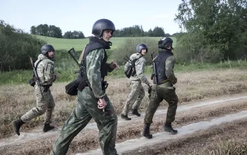 Weißrussische Soldaten in Tarnung und Helmen mit Waffen vor einer Kulisse von Feldern, neue Luftlandesturmtruppe an der Grenze zu Ukraine