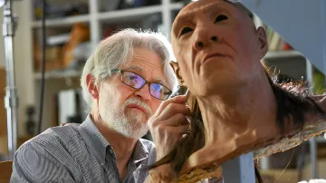 Anthropologist examining a reconstruction of an ancient human face, illustrating the discovery of unknown species in the Homo sapiens genome