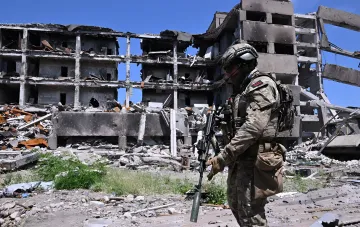 Soldier in full gear stands before the ruins of a multi-story building, symbolizing heavy losses and the failure of offensive operations in July 2026