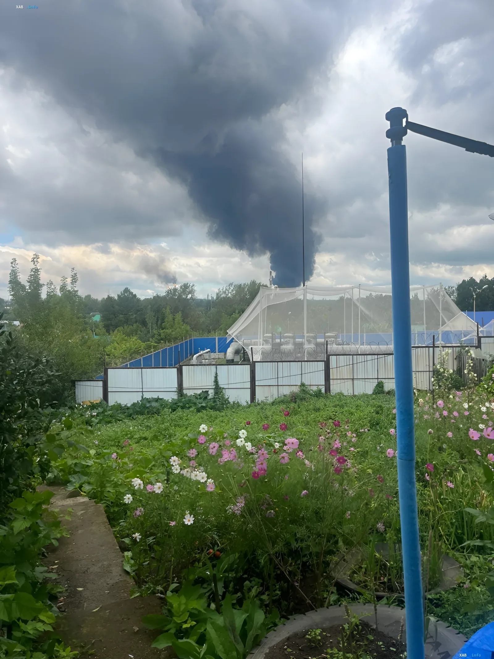Thick black smoke over Bashneft-UNPZ plant in Ufa after drone attack, viewed from flower garden