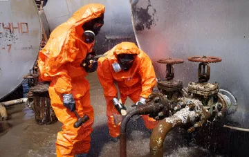 Rescuers in orange protective suits addressing a chemical leak at an industrial site in Poltava region after shelling