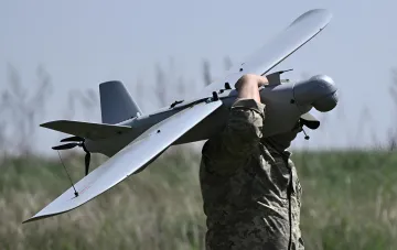 Soldier lifts strike drone for launch, symbolizing attacks on Russian rear areas