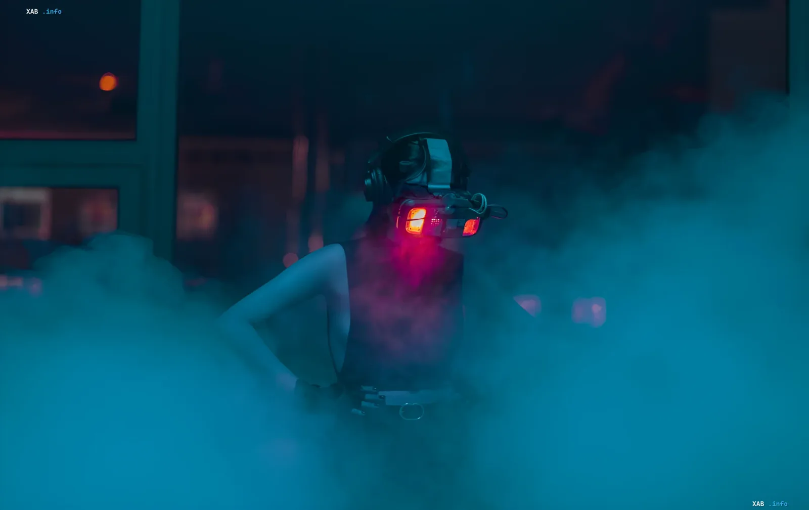 Person in futuristischen Nachtsichtbrillen mit Vollfarbdisplay, beleuchtet von rotem Licht, vor einem rauchigen neonbeleuchteten Innenraum