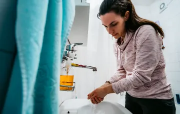 Woman washing hands at bathroom sink — illustration for article on utility bills for IDPs: when it’s legal not to pay for water, electricity and gas