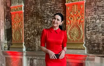 Lyudmyla Barbir in einem roten Satin-Kleid der ukrainischen Marke Vovk: elegantes Outfit vor architektonischen Details