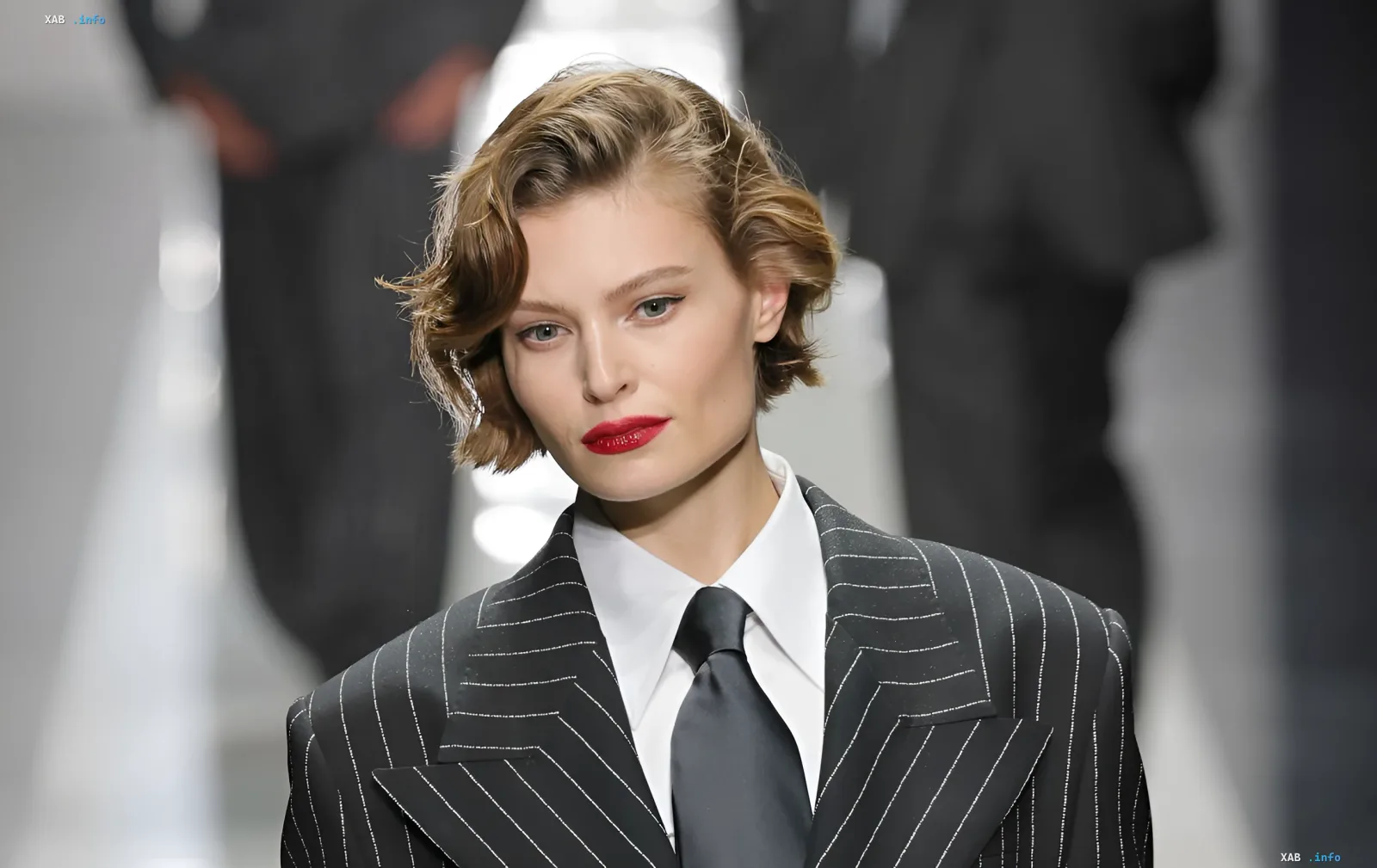 Model in einem strengen gestreiften Blazer mit rotem Lippenstift — Trend Herbst-Winter 2026/2027