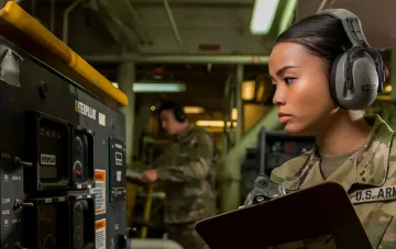 US-Nationalgarde-Soldatin mit Schutzhörnern überwacht Caterpillar-Generatorbetrieb zur Sicherstellung der Stromversorgung kritischer Infrastruktur im Rahmen von Anduril-Drohnenabwehrsystemen