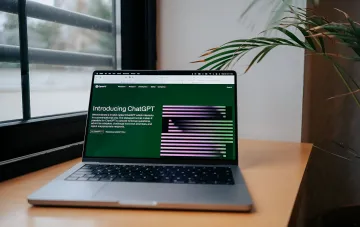 Laptop mit geöffnetem OpenAI-Webseite, auf der ChatGPT vorgestellt wird — der Prototyp zukünftiger „lebender“ sprachgesteuerter Geräte von Jony Ive
