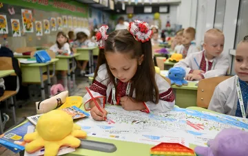 Первоклассница в украинской вышиванке рисует в классе, иллюстрируя тему школьного пакета на 5000 гривен