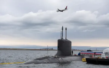 Amerikanisches Atom-U-Boot auf der Wasseroberfläche mit einem Flugzeug im Hintergrund, das die massiven Investitionen des Pentagons in die U-Boot-Flotte veranschaulicht