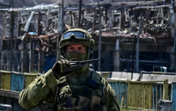 Российский военный в защитной экипировке на фоне разрушенной инфраструктуры, иллюстрирующий напряженность в Донбассе и риск потери Константиновки