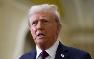 Дональд Трамп в деловом костюме с американским флагом на лацкане, обсуждающий ультиматум Ирану