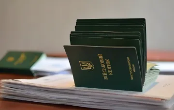 Украинские военные билеты (Військовий квиток) на столе — символ проверки документов призывников в условиях закрытия консульств