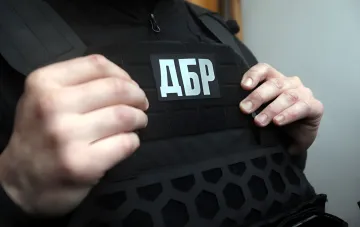 Сотрудник ДБР прикрепляет нашивку с аббревиатурой «ДБР» на тактическую жилетку — символ расследования заказного убийства судьи в Одессе