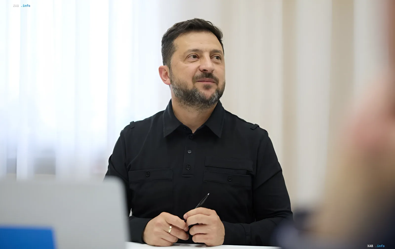 Президент Украины Владимир Зеленский в черной рубашке сидит за столом, задумчиво глядя в сторону, обсуждая стратегию завершения войны до зимы 2026 года.
