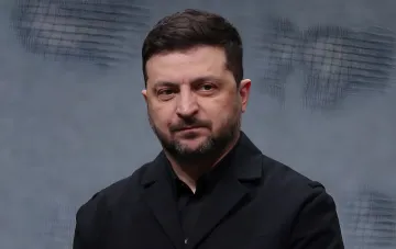 Президент Украины Владимир Зеленский в черном костюме на фоне экрана, обсуждает дипломатическую стратегию против союза России и Китая