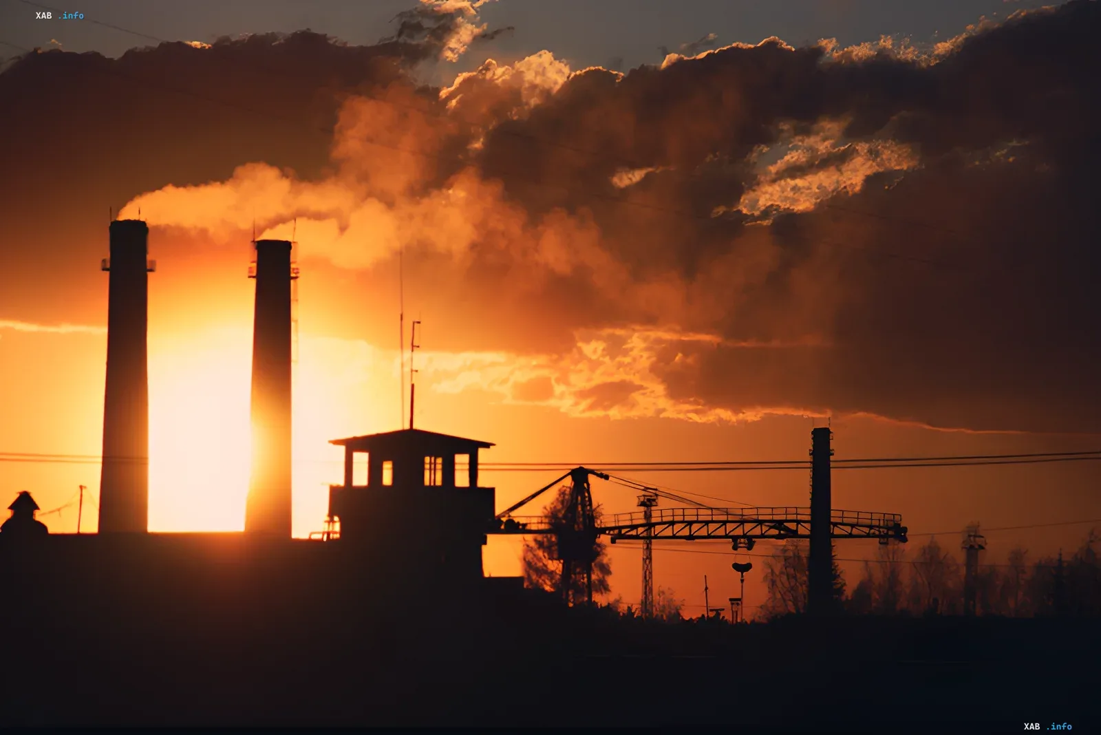 Schornsteine einer Industrieanlage bei Sonnenuntergang, die Umweltbedenken bezüglich des Rechenzentrumsprojekts von Amazon und Duke Energy in North Carolina symbolisieren