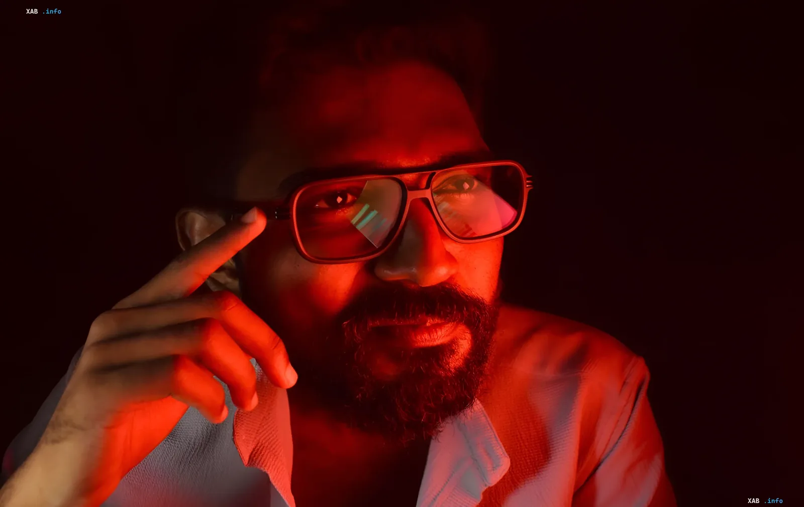 Man in red light holding smart glasses reflecting data — illustration for news about Apple shifting to fitness functions to reduce concerns over hidden recording