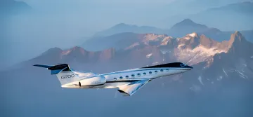 Gulfstream G700 business jet in flight over mountains, showcasing record-breaking speed on transatlantic route