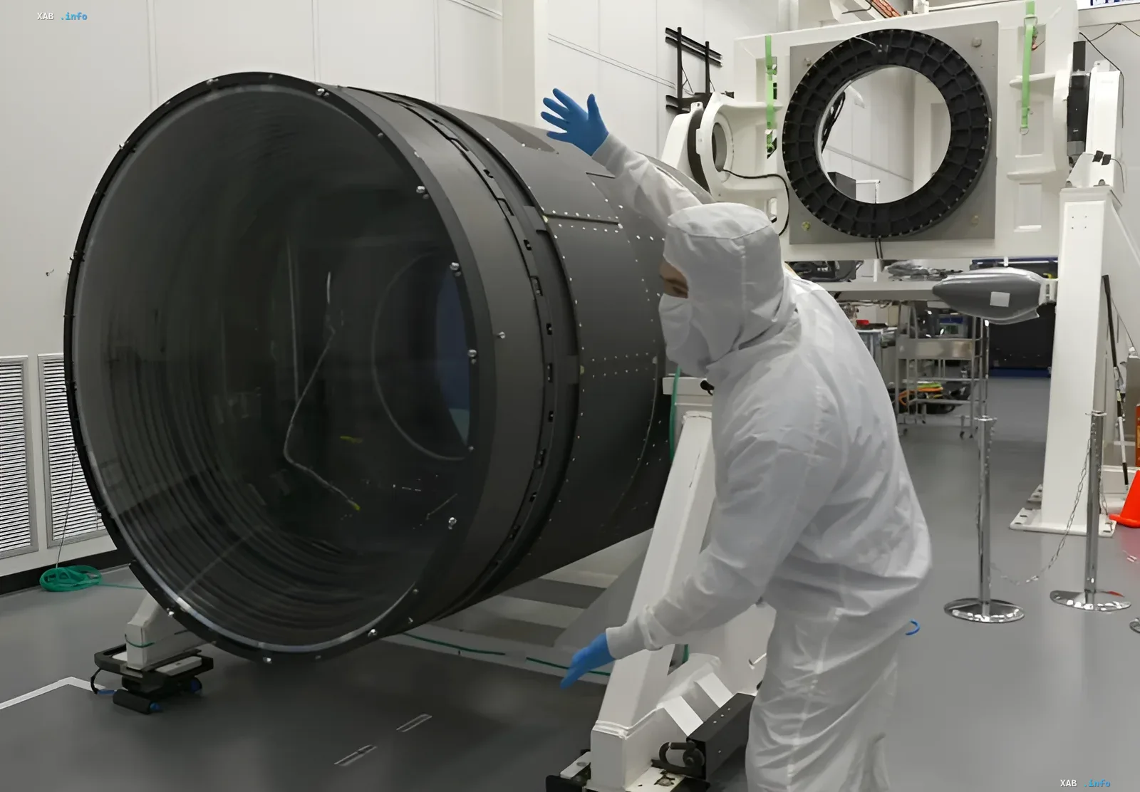 Engineer in a clean suit inspects the giant lens of the LSST camera in the lab