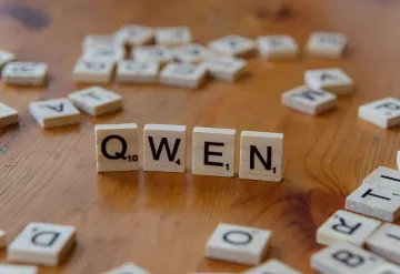 Buchstaben QWEN auf hölzernen Scrabble-Steinen, die das KI-Modell Qwen von Alibaba im Kontext des chinesischen technologischen Durchbruchs symbolisieren